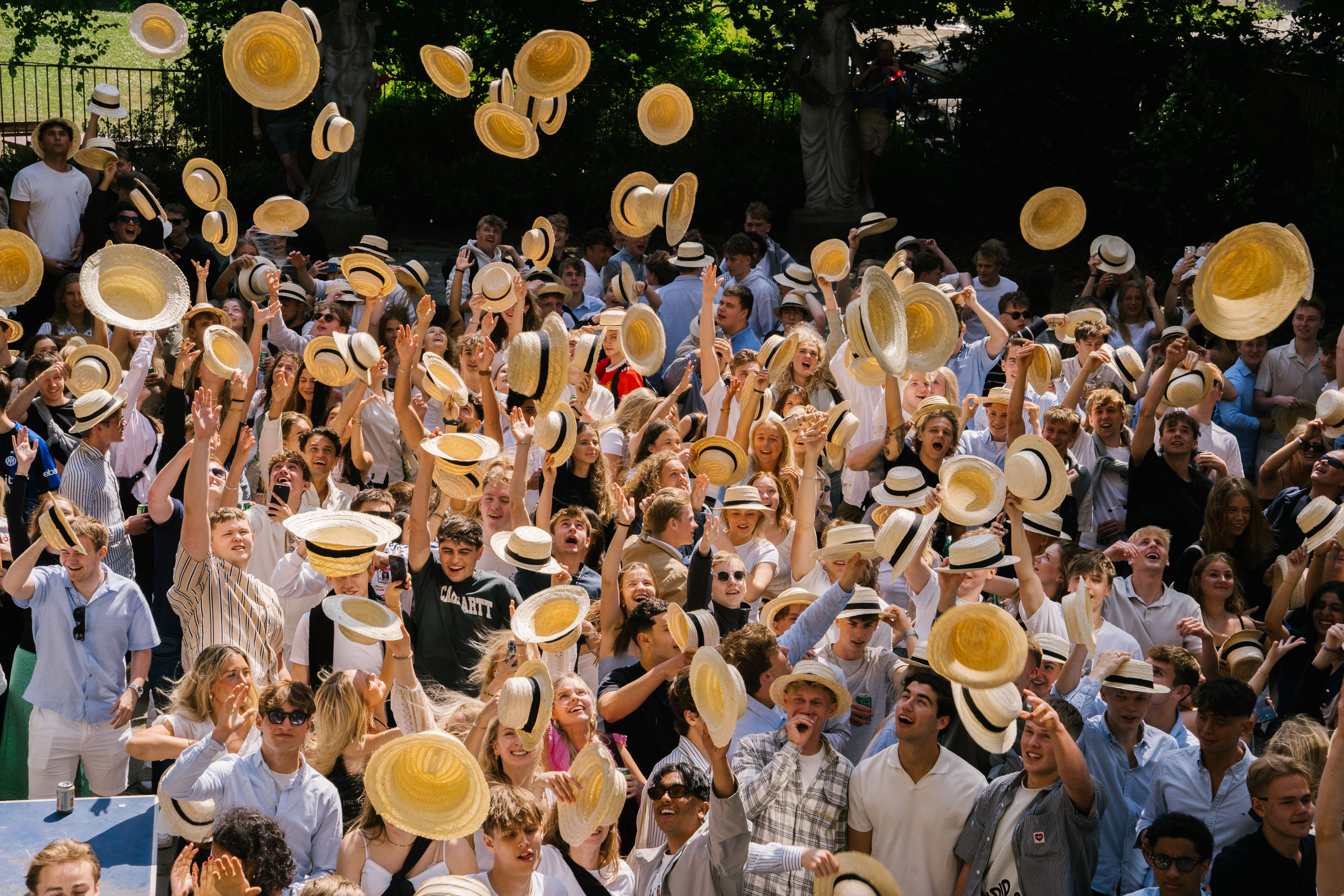 Elever kaster deres stråhatte op i luften til stråhattedag