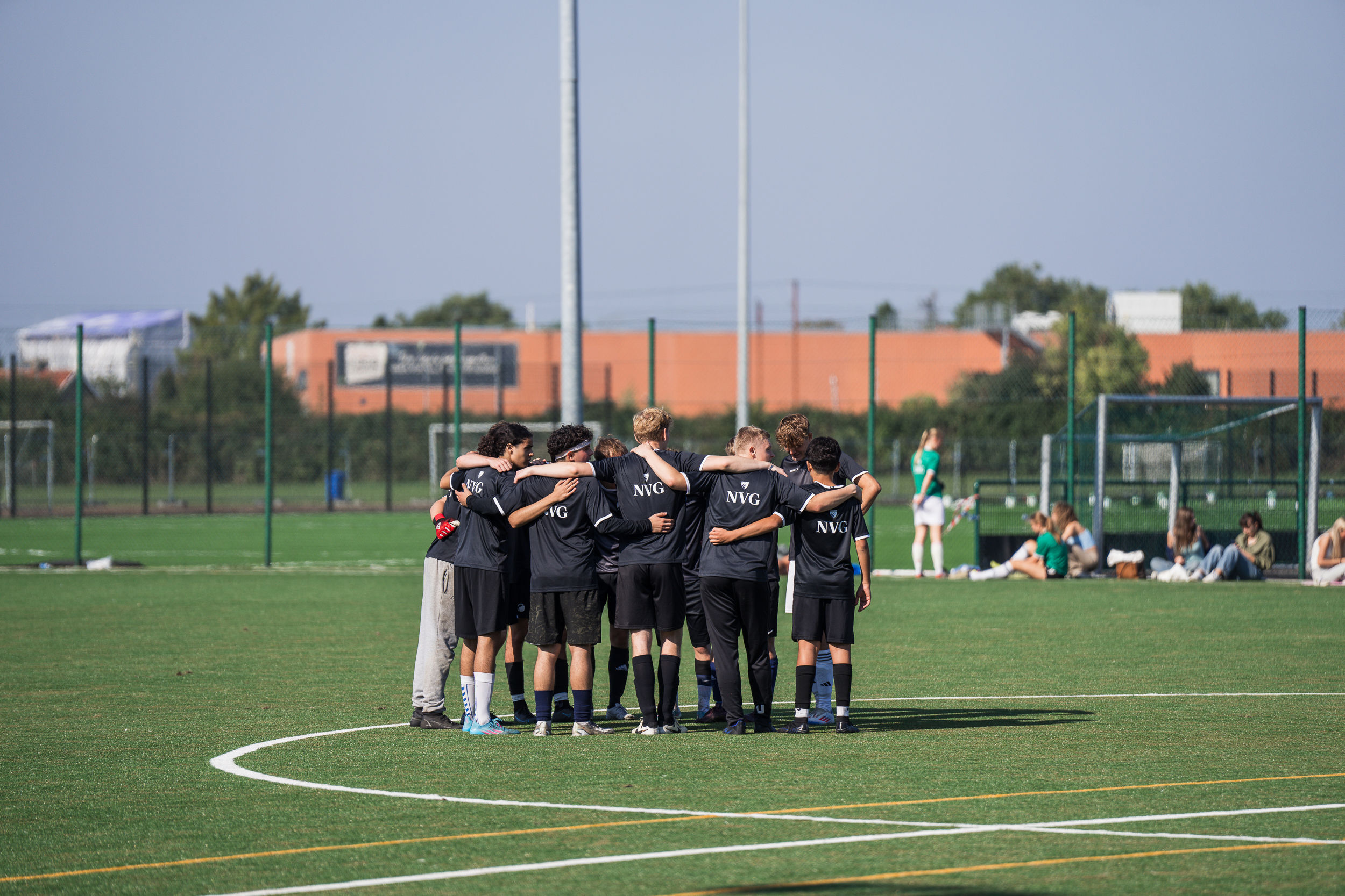 Elever står i rundkreds på en fodboldbane til Niels Brock Cup