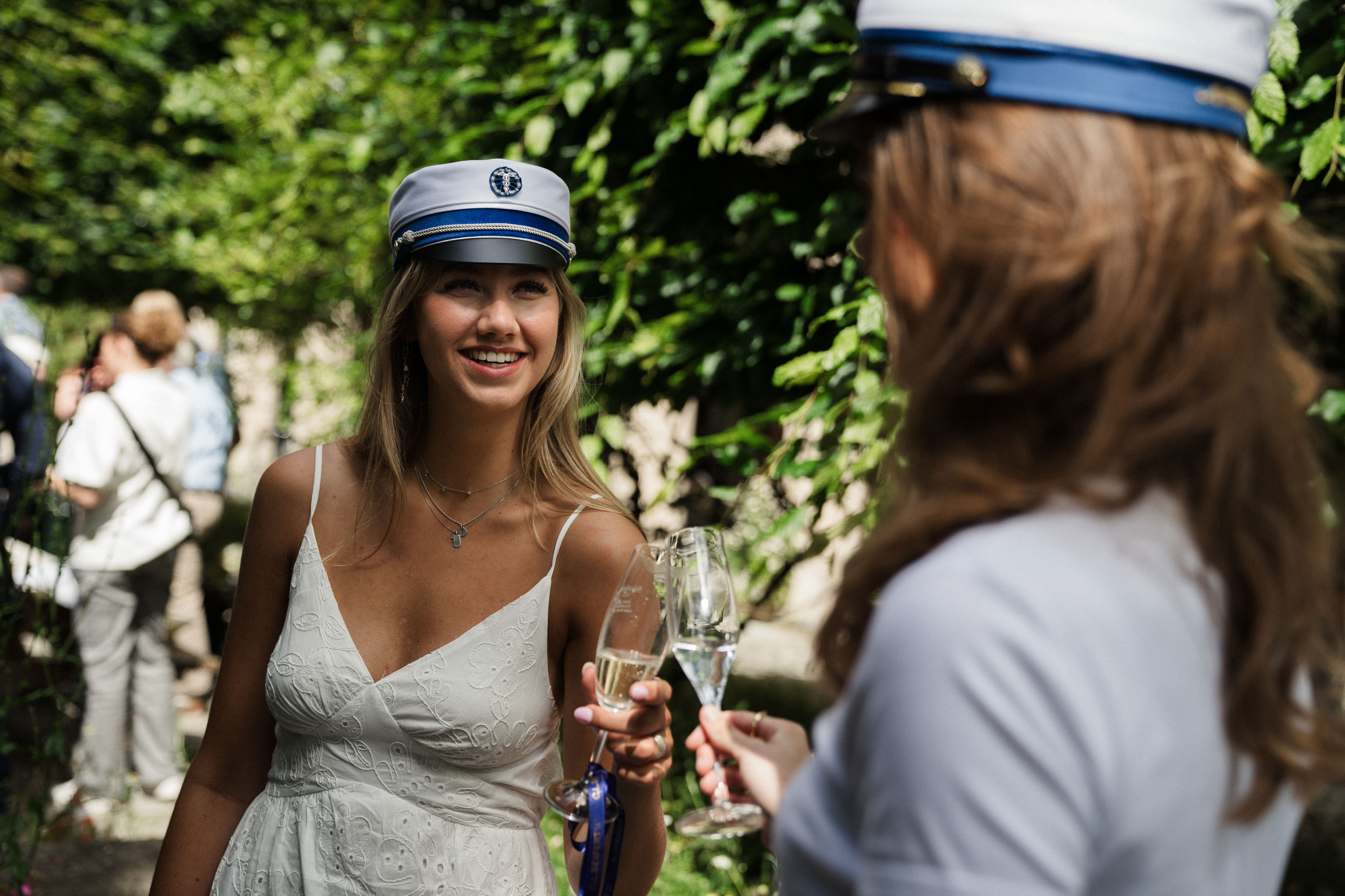 To elever står med studenterhue på og får et glas champagne