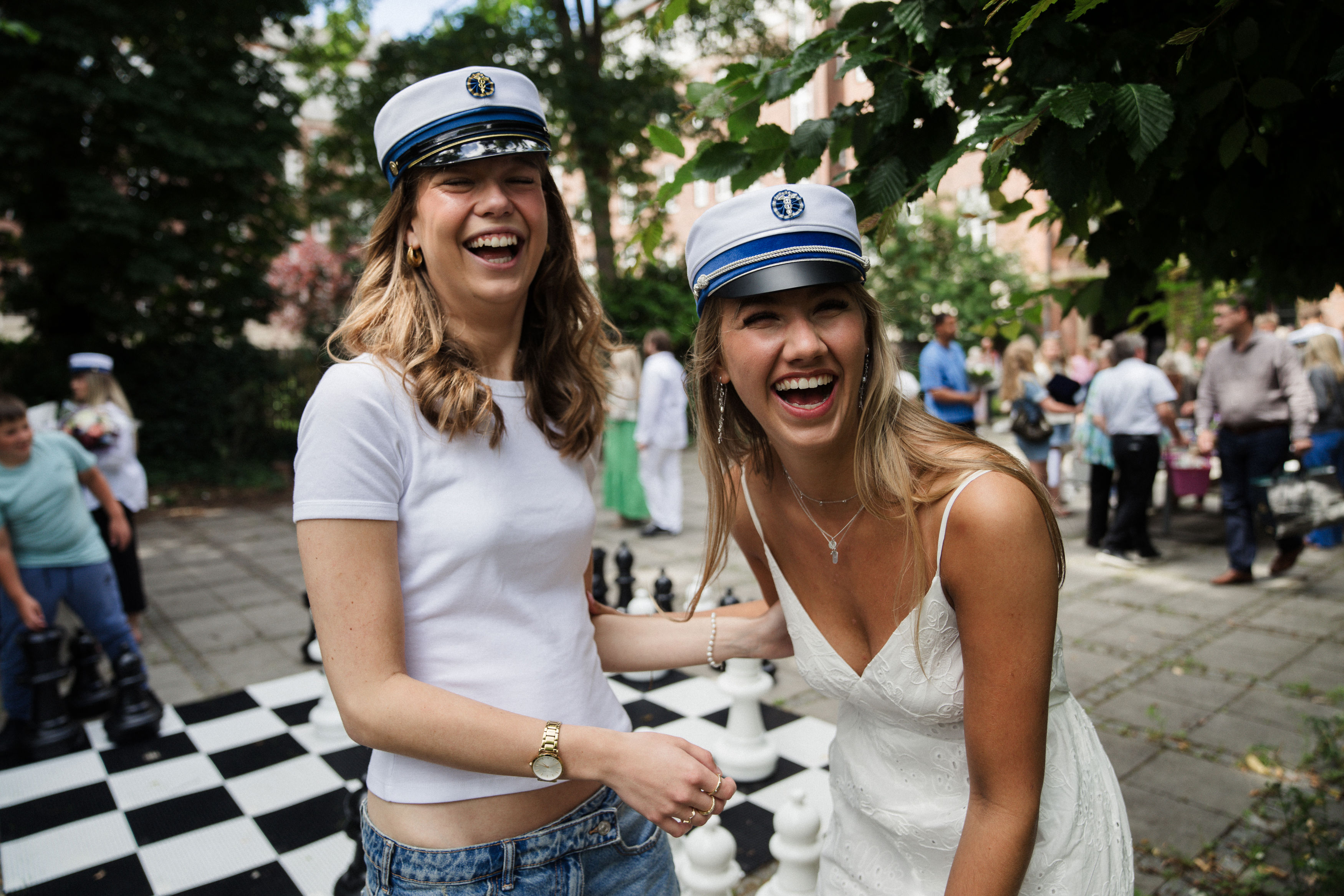 To elever med studenterhue på står og griner